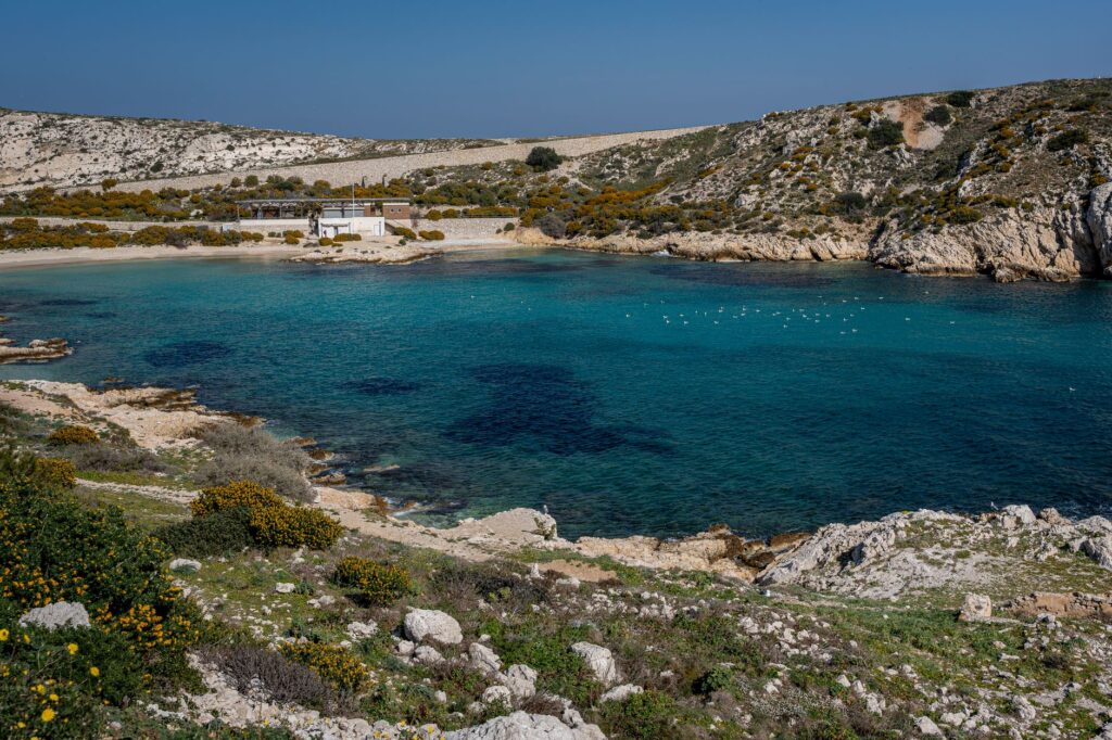 Une crique aux eaux turquoise avec une plage et des collines arides