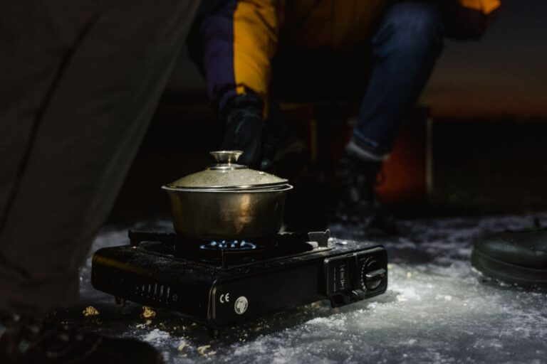 Réchaud de camping allumé avec une casserole sur un sol glacé la nuit.