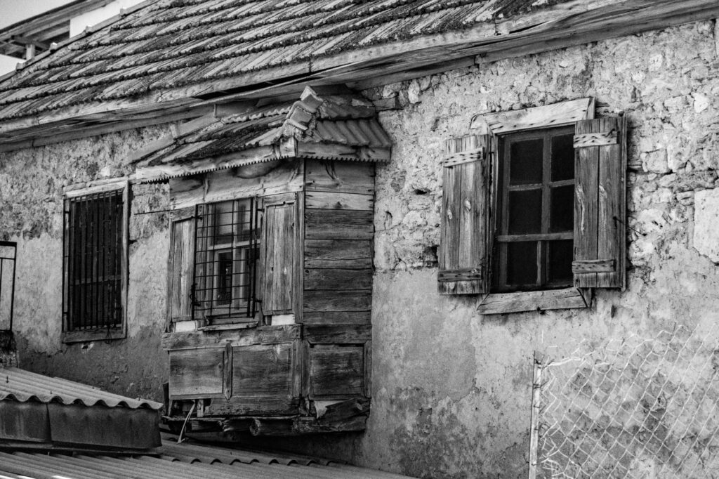 Façade d'une vieille maison en pierre, avec fenêtres et volets en bois