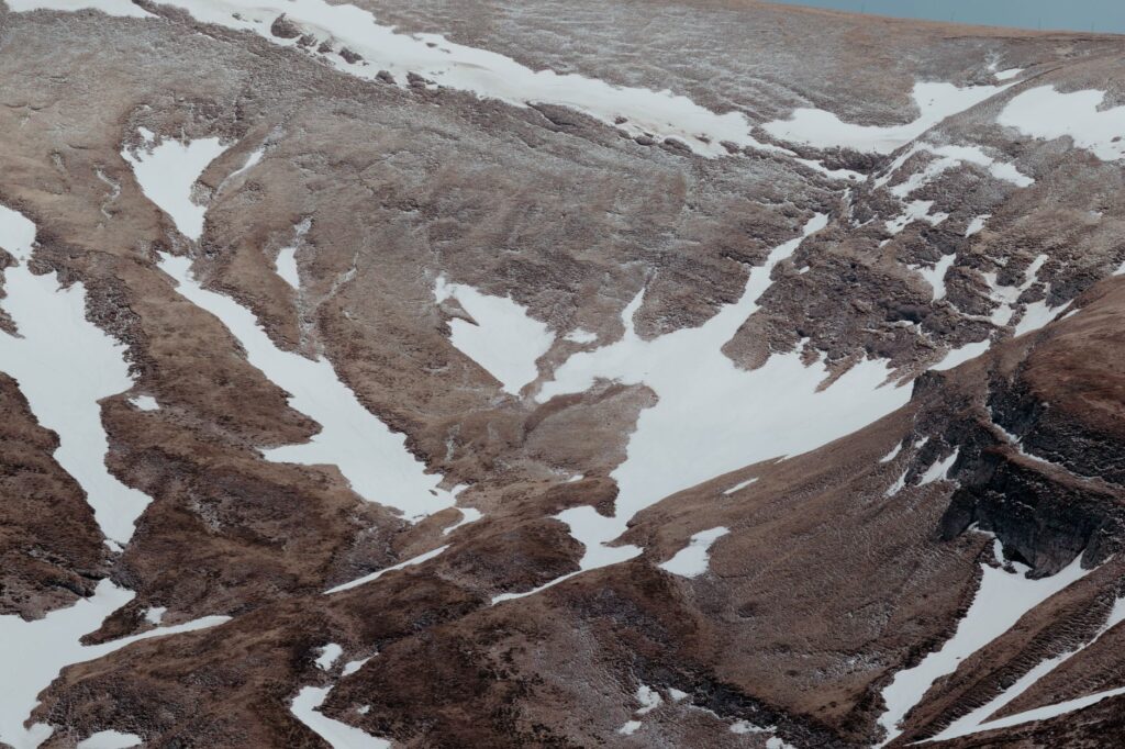 Pans de montagnes rocheuses et enneigées avec herbe sèche marron.