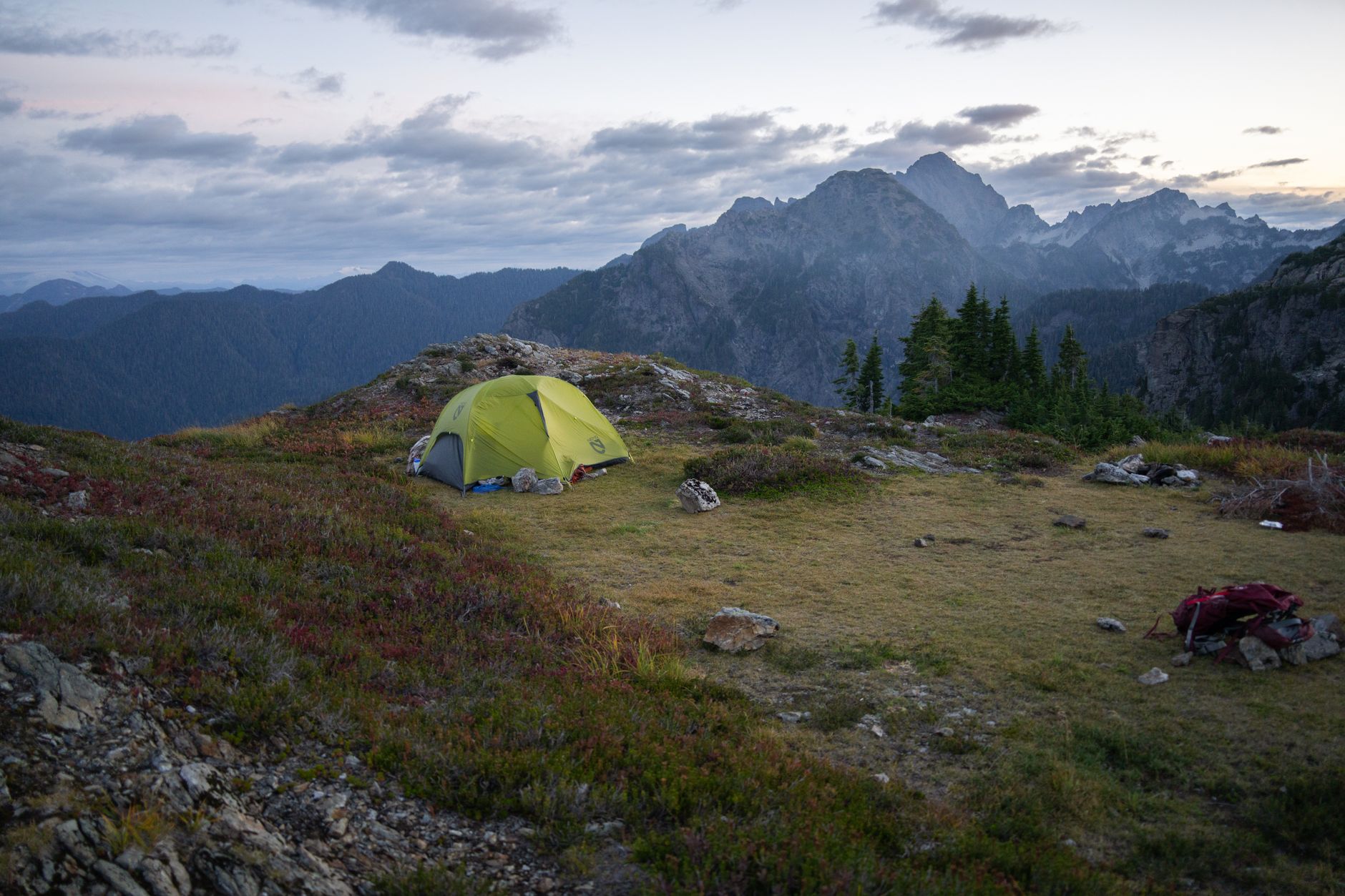 Tente de bivouac jaune sur une crête rocheuse face à des montagnes