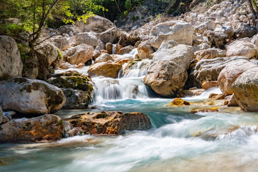 Rivière de montagne avec des cascades entre des rochers et de la végétation luxuriante.